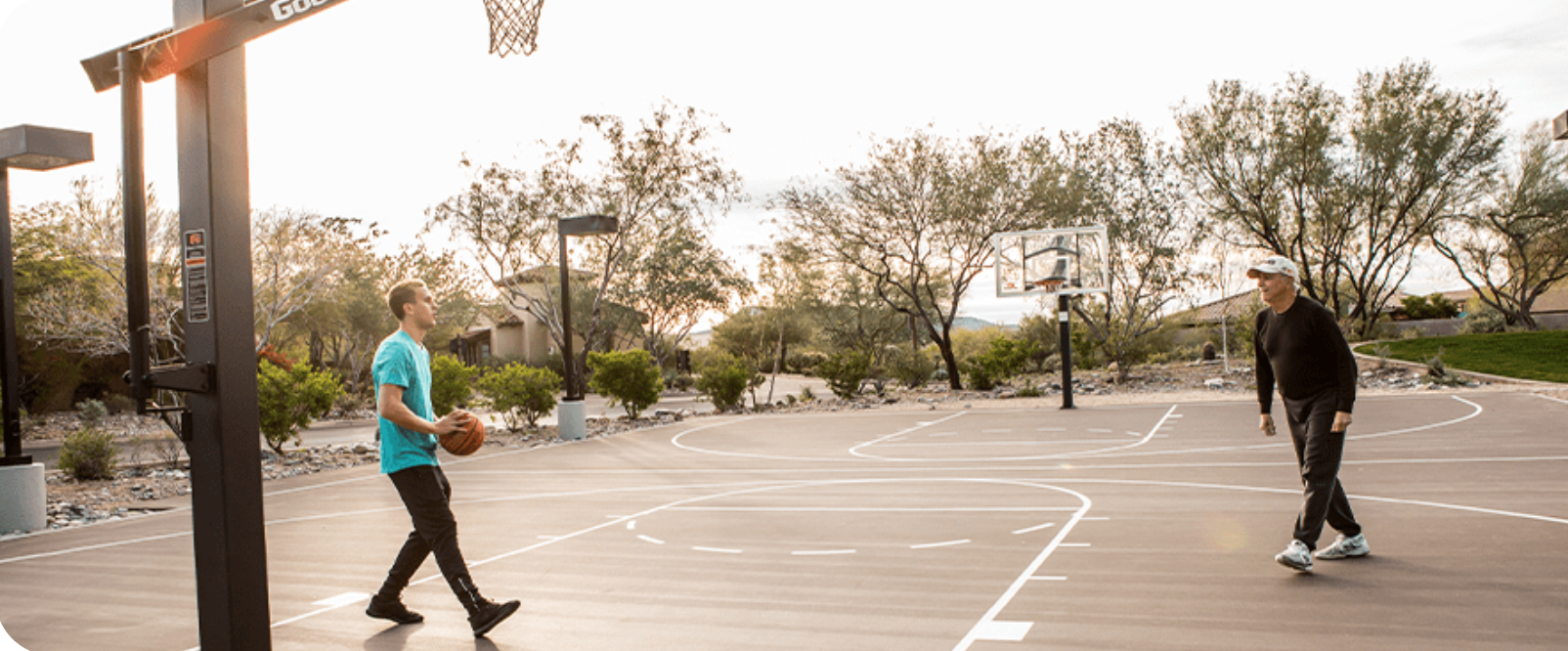 Homestead outdoor basketball court at dusk with two players