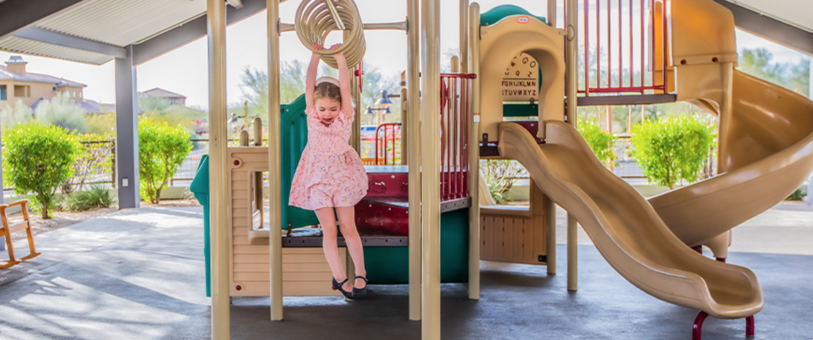 Homestead covered playground — child on climbing structure under shade canopy